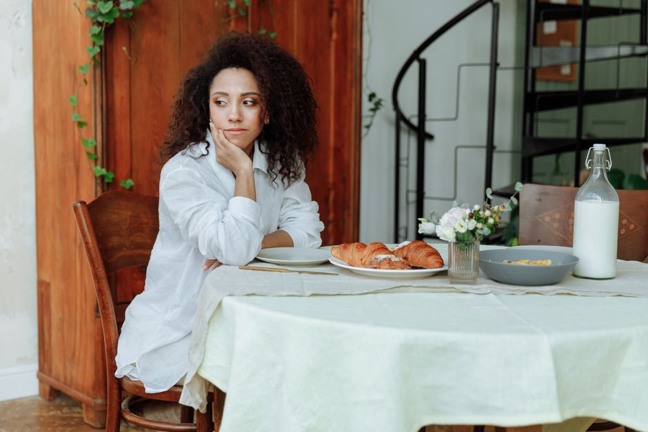 Woman sitting thoughtfully near a plate of pastries