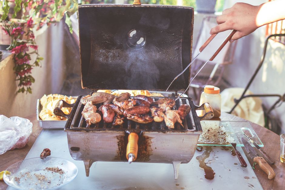 Kød og pølser tilberedes på en lille udendørs grill