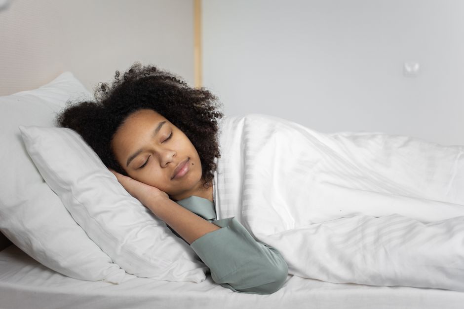 En kvinde sover roligt i sin seng i blødt morgenlys