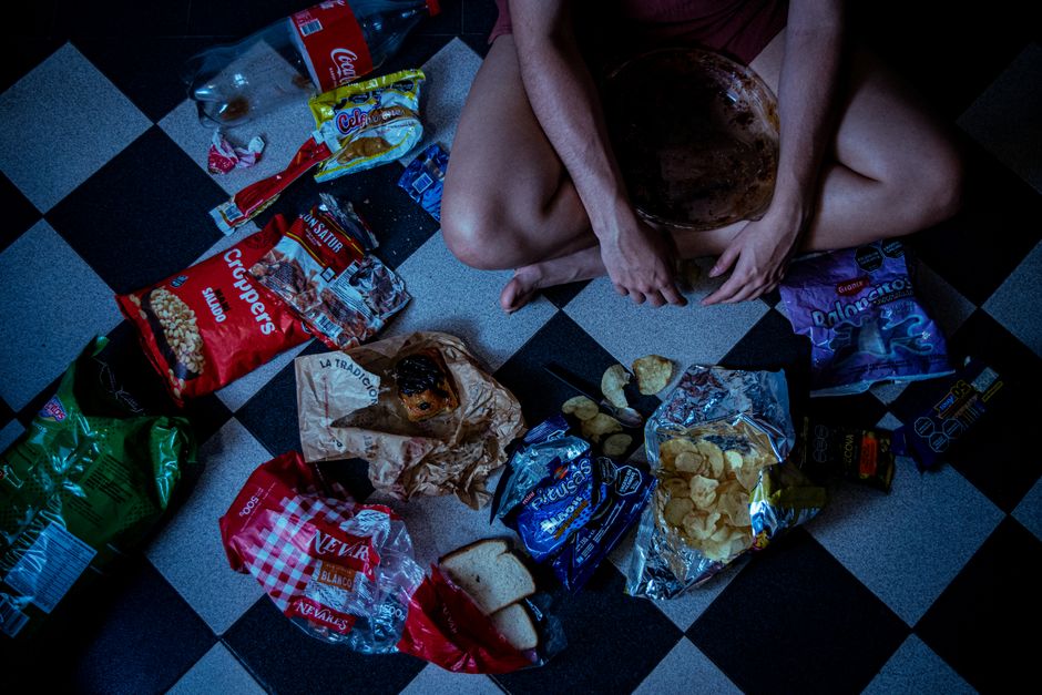 Man sitting on the floor surrounded by snack food