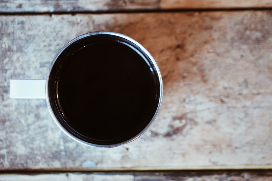 En kop sort kaffe set oppefra på et træbord