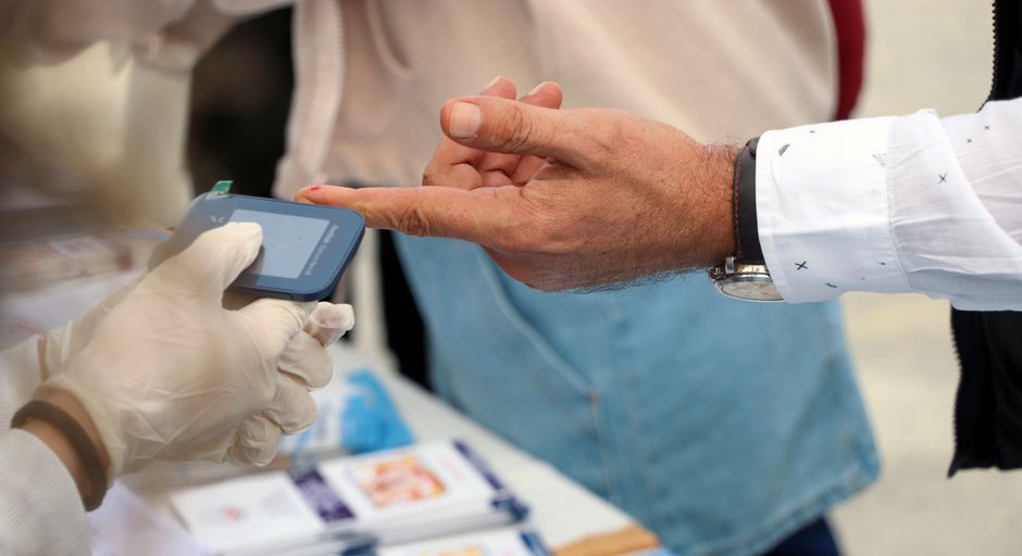 En sundhedsmedarbejder måler en persons blodsukker med et fingerprik-apparat