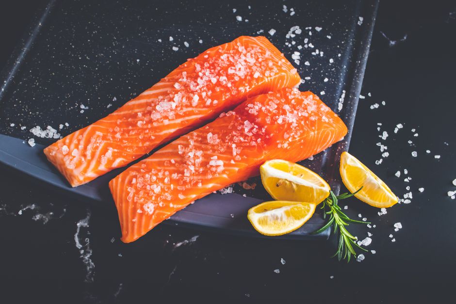 Rå laksefileter med citronbåde på en bageplade