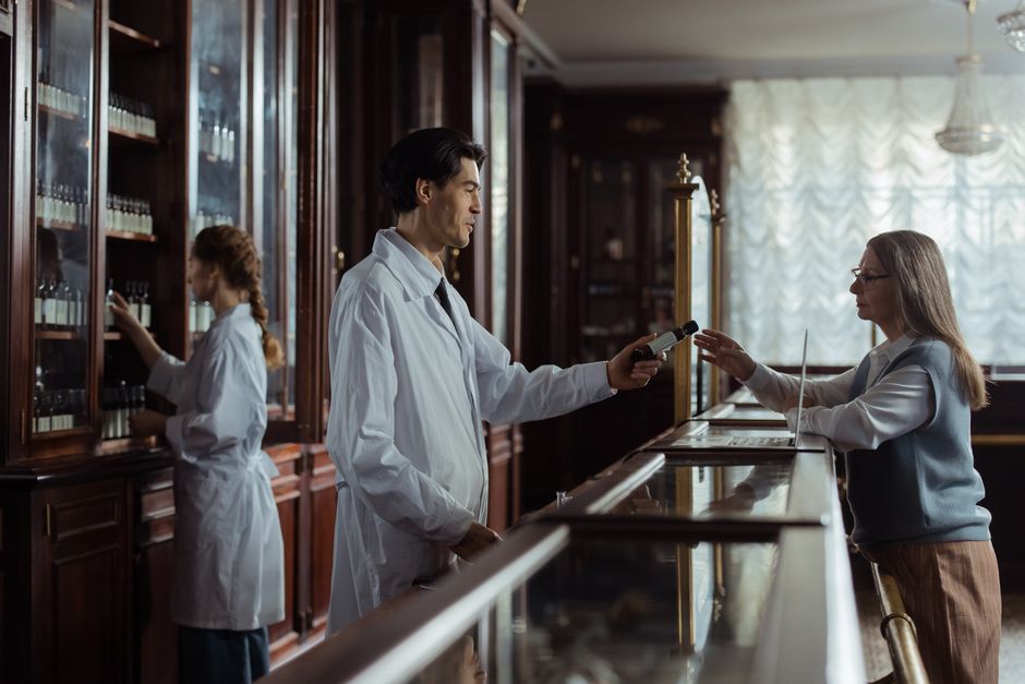 En farmaceut rækker en lille medicinbeholder til en patient