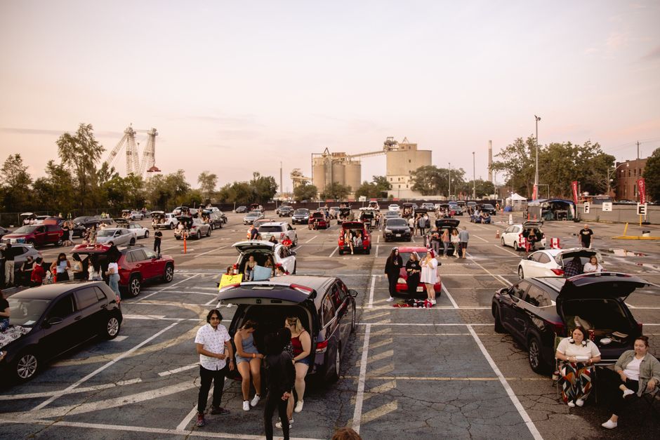 Friends gathered around a grill in a parking lot before a game