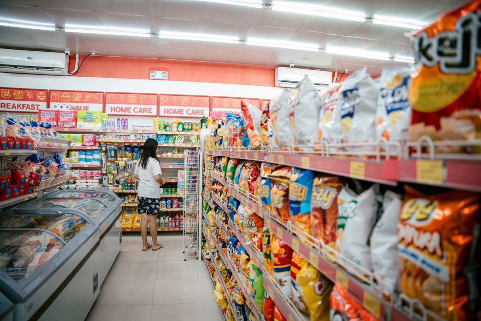 En kunde står i en supermarkedsgang fyldt med emballerede snacks