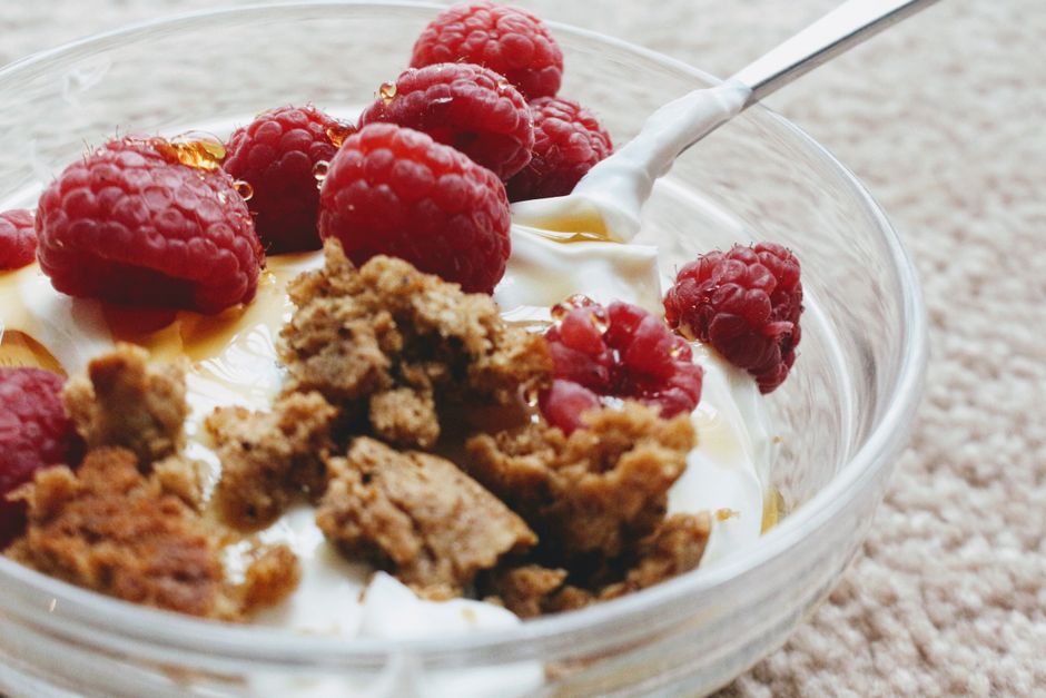 En skål yoghurt toppet med hindbær og granola